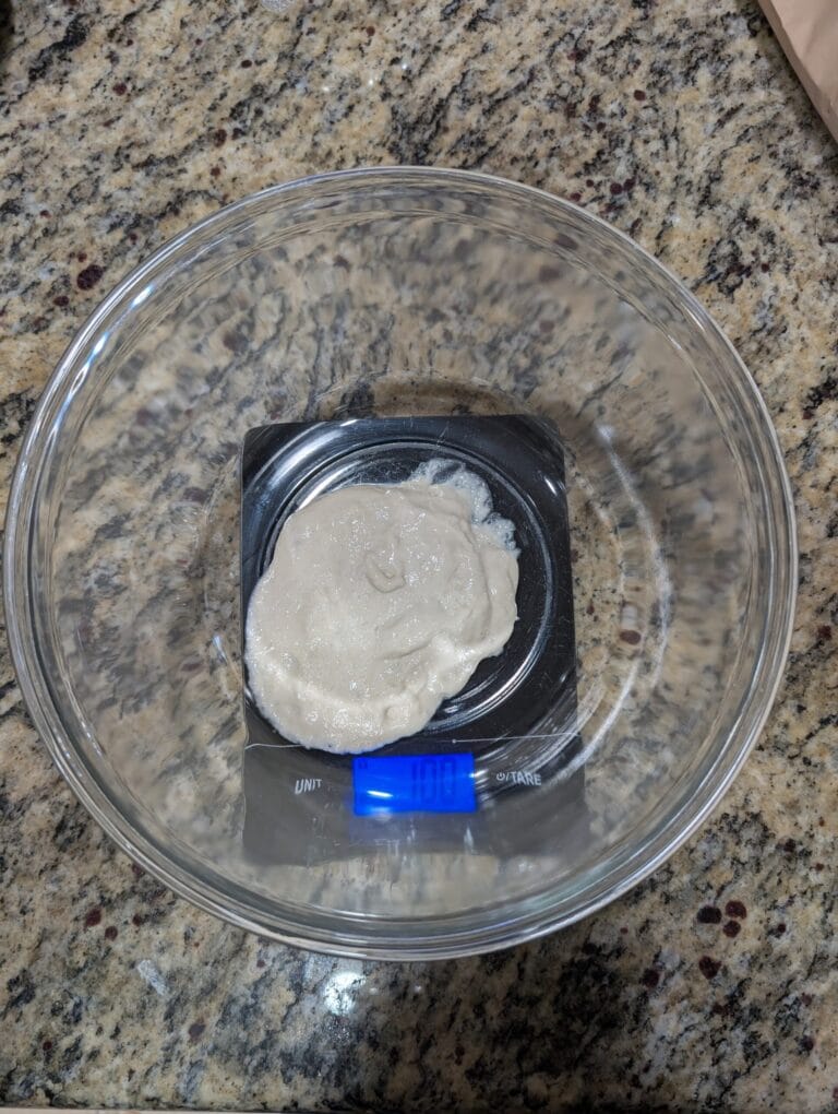 Active bubbly sourdough starter in a clear glass bowl ready to mix into bread dough