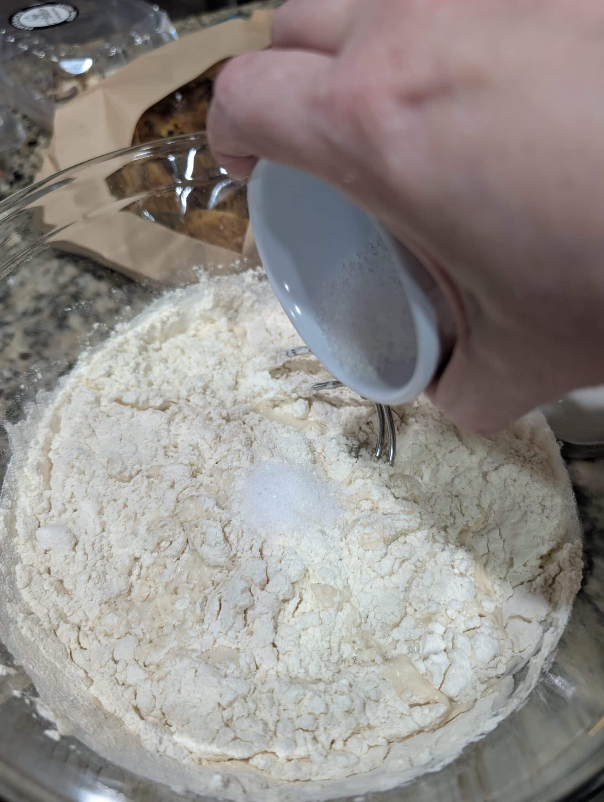 Adding fine sea salt to flour in a mixing bowl for beginner sourdough bread