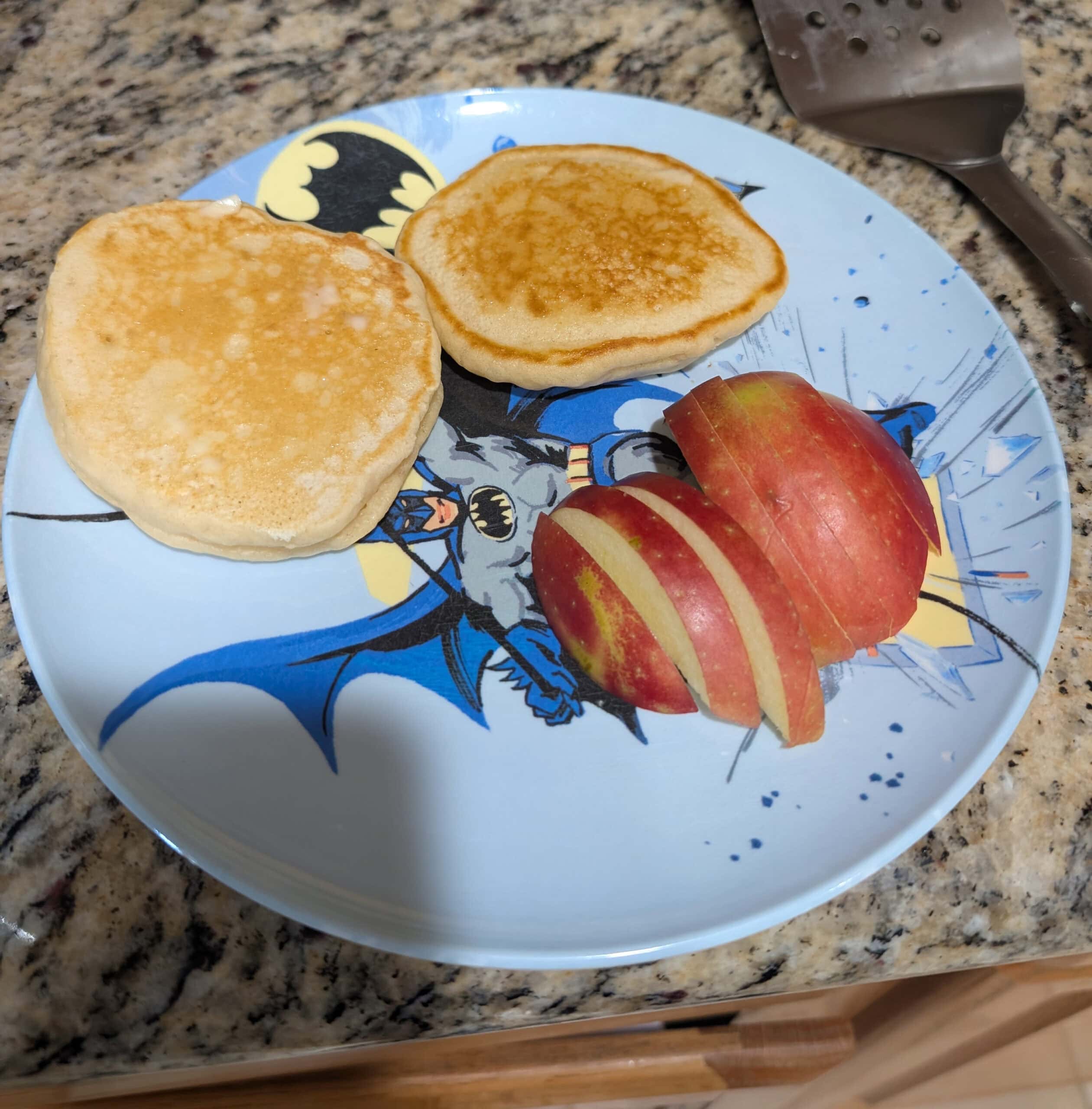 Sourdough pancakes cooking on a hot flat top griddle with bubbles forming across the surface