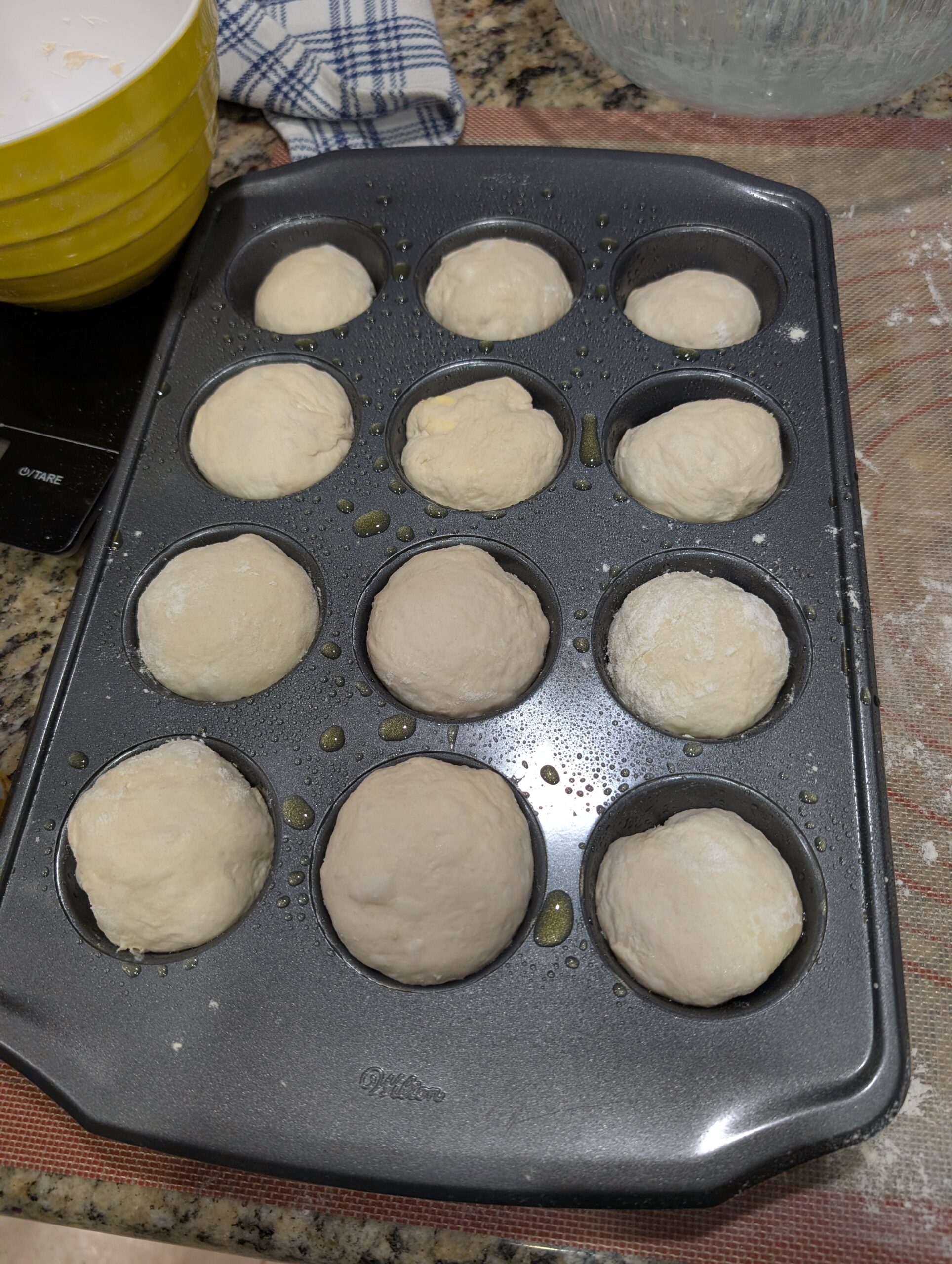 Twelve baked sourdough pull-apart rolls in a muffin tin with golden brown tops fresh from the oven